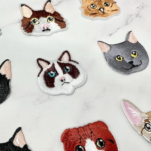 Peut inclure: Un ensemble de dix patchs brodés thermocollants représentant différents visages de chats. Les patchs sont blancs, noirs, gris, bruns et orange. Les chats ont des expressions différentes, notamment surprise, endormie et joueuse.