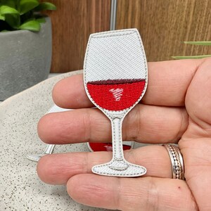 Peut inclure: Patch thermocollant brodé blanc représentant un verre à vin rempli de vin rouge.