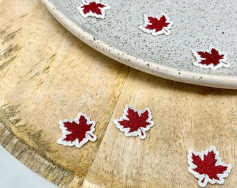 Pode incluir: Um conjunto de patches de ferro de folha de bordo vermelho em uma superfície de madeira e um prato branco.