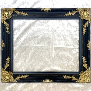 Marco rococó de madera y yeso, fino y ornamentado, en negro y dorado.