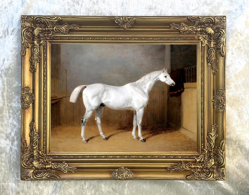May include: A framed oil painting of a white horse standing in a stable. The horse is facing to the right and has a long, flowing mane and tail. The painting is set in a gold frame with ornate details.