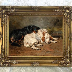 May include: An antique oil painting in a gold ornate frame depicts two dogs resting. One dog is black with brown markings, and the other is white with brown spots. The dogs are lying on a brown surface.