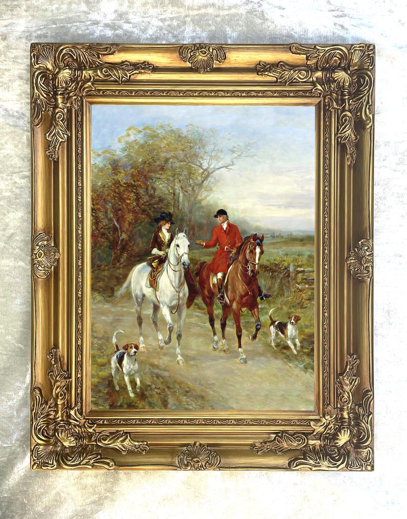 Puede incluir: Una pintura al &oacute;leo en un marco dorado decorativo que representa a dos jinetes a caballo, uno en un caballo blanco y otro en uno marr&oacute;n, acompa&ntilde;ados por dos peque&ntilde;os perros de caza en un camino de tierra rodeado de &aacute;rboles y campo.