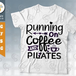 May include: White t-shirt with black text that reads "Running on Coffee and Pilates". The text is decorated with small hearts and an arrow.
