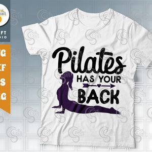 May include: White t-shirt with black text that reads "Pilates has your back". A purple silhouette of a person doing a pilates pose is below the text.