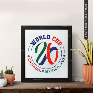 May include: A framed print with the text "WORLD CUP 26" in blue, green, and red. The design includes the text "CANADA, MEXICO, USA" in a circular pattern. The frame is black, and the background is white.