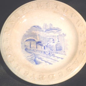 May include: A vintage blue and white ceramic plate with a train engine and train cars in a tunnel. The plate has a white background with a blue border that reads "D.R.G. & C.R.R.  1851".