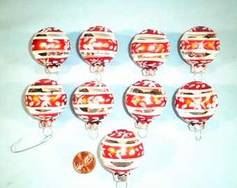 May include: A collection of nine vintage Christmas ornaments. Each ornament is a red and white striped sphere with silver accents and a floral design. The ornaments are suspended by silver hooks.