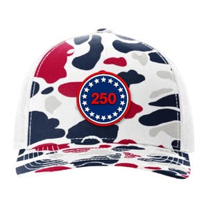 May include: A white trucker hat with a camouflage pattern in red, navy, and gray. The hat features a circular patch with the number "250" in red, surrounded by white stars on a navy background.