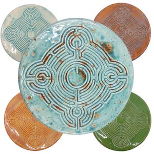 May include: Five ceramic plates with a raised design of a labyrinth pattern. The plates are in various shades of blue, green, and orange.