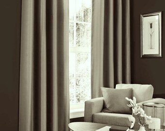 May include: A pair of brown blackout curtains with silver grommets hanging in a living room with a brown wall, a window, a couch, and a coffee table.