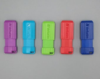 May include: Five USB flash drives in different colors: purple, blue, green, red, and blue. Each drive has the word "Verbatim" printed on it.