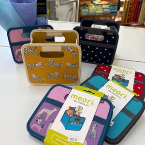 May include: A collection of colorful, mini foldable boxes with various patterns, including dalmatian spots and dog illustrations. The boxes have handles and are displayed with their packaging, which includes the text "meori Mini Foldable Box" and "Mini but Mighty".