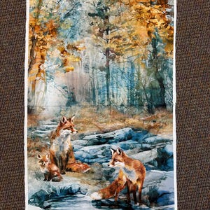 May include: A fabric panel featuring a watercolor painting of a forest scene with three foxes. The artwork showcases a family of foxes near a stream, with autumn foliage in shades of orange and gold. The background depicts a misty forest.
