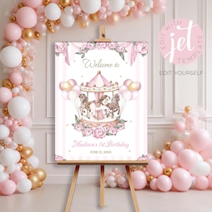 May include: A pink and white welcome sign for a birthday party, featuring a carousel illustration with horses and balloons. The sign is on an easel, surrounded by pink and gold balloons. Text on the sign reads "Welcome to" and "Madison's 1st Birthday".