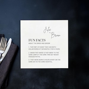 Pode incluir: Um cartão quadrado branco sujo com os nomes "Julie + Brian" em escrita elegante. O cartão apresenta "FUN FACTS ABOUT THE BRIDE AND GROOM" e três fatos numerados sobre o casal. Um garfo e uma faca são visíveis à esquerda.