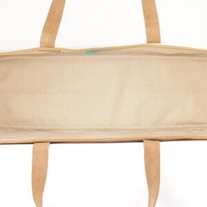An empty tote bag with a tan interior and a brown exterior, featuring a handle and straps.