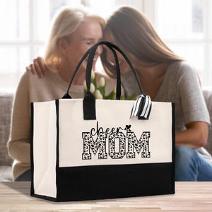 a woman sitting on a couch next to a woman holding a black and white bag