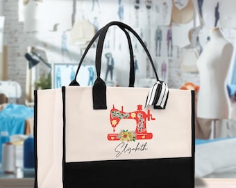 Peut inclure: Un sac fourre-tout crème avec un fond et des poignées noirs. Il présente un motif de machine à coudre rouge, des tournesols et le nom "Elizabeth". Un ruban rayé noir et blanc est attaché à la poignée.