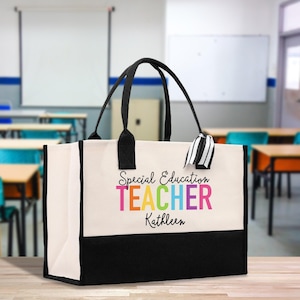May include: A canvas tote bag with black handles and a black base. The bag has the text "Special Education TEACHER Kathleen" in colourful letters. A black and white striped ribbon hangs from the handle.