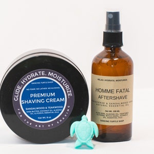 May include: Two grooming products for men. A black jar with a white label that reads "Glide. Hydrate. Moisturize. For the Art of Shaving. Premium Shaving Cream. Sandalwood & Teakwood. Shea Butter, Coconut Oil, Almond Oil, Glycerin, Essential Oils. Net Wt. 8 oz." and a clear glass bottle with a brown label that reads "Relax. Hydrate. Moisturize. Homme Fatal Aftershave. Incense & Sandalwood Vanilla. Natural Essential Oil. Net Wt. 100 ml. Aloe Vera, Almond Oil, Vegetable Glycerin, Witch Hazel, Vitamin E Oil, Essential Oils. Dancing Turtle Shop."