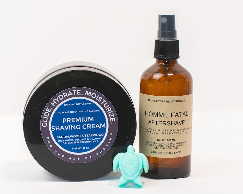 May include: Two grooming products for men. A black jar with a white label that reads "Glide. Hydrate. Moisturize. For the Art of Shaving. Premium Shaving Cream. Sandalwood & Teakwood. Shea Butter, Coconut Oil, Almond Oil, Glycerin, Essential Oils. Net Wt. 8 oz." and a clear glass bottle with a brown label that reads "Relax. Hydrate. Moisturize. Homme Fatal Aftershave. Incense & Sandalwood Vanilla. Natural Essential Oil. Net Wt. 100 ml. Aloe Vera, Almond Oil, Vegetable Glycerin, Witch Hazel, Vitamin E Oil, Essential Oils. Dancing Turtle Shop."
