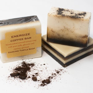 May include: Two bars of handmade coffee soap with a brown label that reads "Energize Coffee Bar" and "Handcrafted natural artisan soap with goat milk, glycerin and espresso grounds" and "Dancing Turtle Shop".