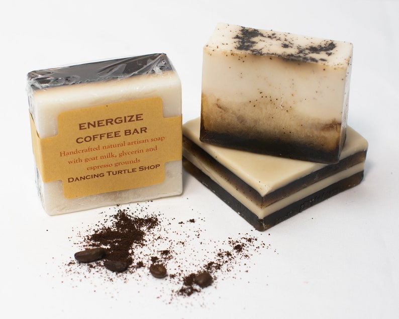 May include: Two bars of handmade coffee soap with a brown label that reads "Energize Coffee Bar" and "Handcrafted natural artisan soap with goat milk, glycerin and espresso grounds" and "Dancing Turtle Shop".