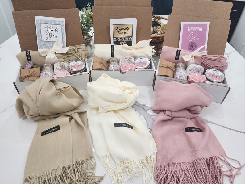 May include: Three gift boxes with different coloured cashmere scarves, each box contains bath products and a card with a different message. The cards say "Thank You", "Especially For You", and "Thinking of You".