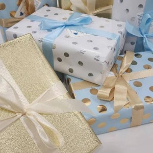 May include: A stack of gift boxes wrapped in blue and gold paper with white polka dots. The boxes are tied with white and blue ribbon.