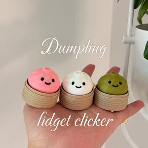 May include: Three colourful dumpling-shaped fidget clickers. The clickers are pink, white, and green, each with a smiling face. They sit in small, tan-coloured baskets. The words "Dumpling" and "fidget clicker" are written on the image.