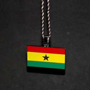 May include: A silver chain necklace with a pendant featuring the flag of Ghana. The flag is red, yellow, and green with a black star in the center.