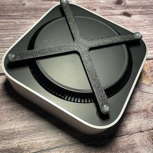 Könnte beinhalten: Ein schwarzer und silberner Computer mit einem schwarzen gummierten Ständer mit vier Gummifüßen. Der Ständer ist so konzipiert, dass der Computer angehoben wird und die Luftzirkulation verbessert wird.