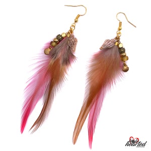 May include: A pair of long feather earrings with pink, brown and gold accents. The earrings feature small heart-shaped charms and beads.