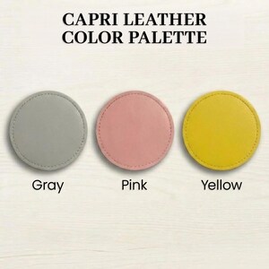 three circular leather coasters with different colors: gray, pink, and yellow.
