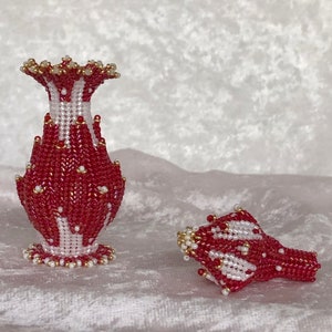 Puede incluir: Dos jarrones de cuentas rojas y blancas con un diseño floral. Los jarrones están hechos de cuentas pequeñas y tienen un acabado brillante.