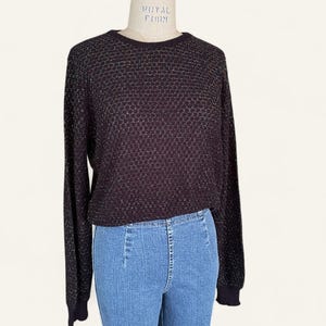 May include: A dark brown long-sleeved sweater with a textured pattern. The sweater is displayed on a mannequin with light blue jeans. The sweater has a round neckline and ribbed cuffs.