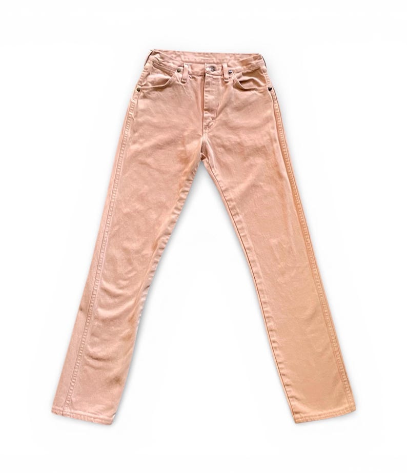 May include: A pair of high-waisted peach-colored denim jeans featuring a classic five-pocket design, a button fly closure, and visible copper-toned rivets at the pocket corners. The pants have a straight-leg cut with stitched seams.