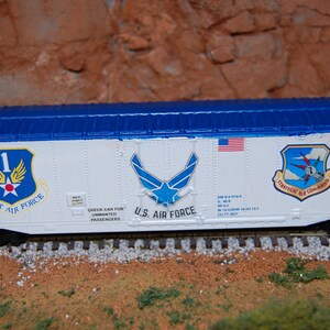 May include: A white boxcar with blue trim and the words "USAF 4500X" and "U.S. AIR FORCE" printed on the side. The boxcar has three different Air Force logos, including the First Air Force logo, the U.S. Air Force logo, and the Strategic Air Command logo.