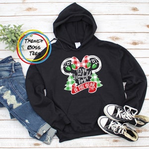 Puede incluir: Sudadera con capucha negra con un lazo de cuadros rojos y blancos y árboles de Navidad de cuadros verdes y blancos. El texto "It's the Wonderful Time of the Year" está impreso en la sudadera.