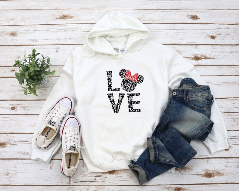 May include: White hooded sweatshirt with a black and white graphic of Mickey Mouse heads forming the word "LOVE" with a red bow on the top of the "O".