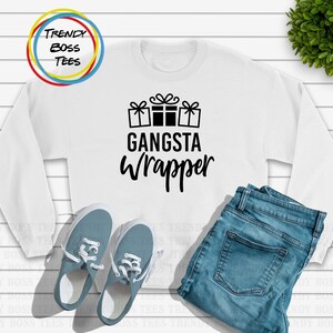 Puede incluir: Sudadera blanca con texto negro que dice "Gangsta Wrapper" y un gráfico de tres regalos envueltos.