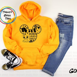 K&ouml;nnte beinhalten: Ein gelber Hoodie mit einer schwarzen Mickey-Maus-Silhouette, die Stitch und den Text "Ohana means family" zeigt.