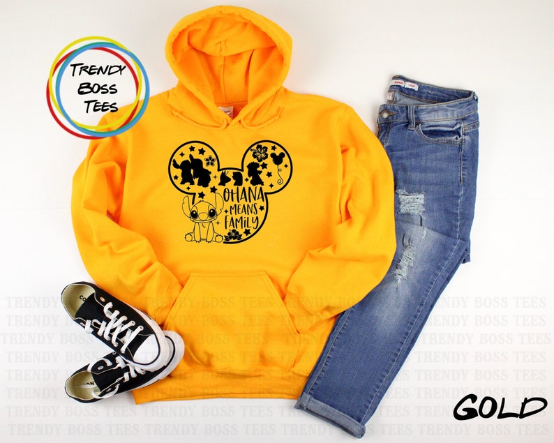 K&ouml;nnte beinhalten: Ein gelber Hoodie mit einer schwarzen Mickey-Maus-Silhouette, die Stitch und den Text "Ohana means family" zeigt.