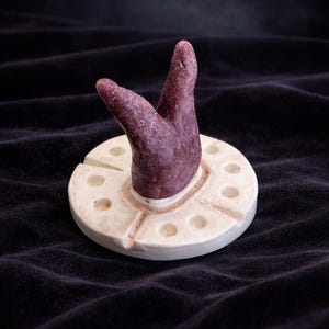 May include: A white ceramic mug with a black handle and the text "But First, Coffee" in a black, handwritten-style font. The mug is on a white surface.