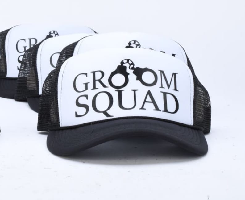 May include: Four black and white trucker hats with a white mesh back. The front of the hats have a black graphic of a soccer ball and the text "Groom Squad".