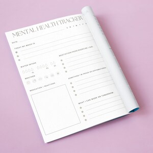 Può includere: Un diario bianco per il monitoraggio della salute mentale con un design nero e grigio. Il diario ha sezioni per tenere traccia dell'umore, dell'assunzione di acqua, del tempo, dei farmaci, della meditazione, del cibo, dell'esercizio fisico, delle cose di cui sei orgoglioso, delle affermazioni e su cosa puoi lavorare domani.