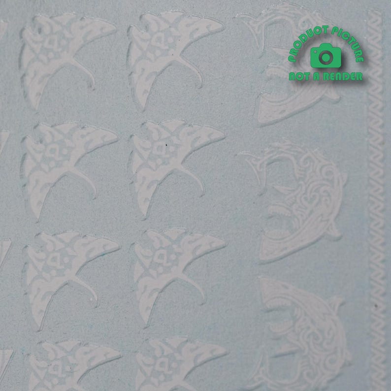 Op de afbeelding: Witte, gepatenteerde stickers met een ontwerp van een mantarog en een vis. De stickers bevinden zich op een lichtblauwe achtergrond.