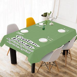 May include: A green tablecloth with the text "Custom Design" and the words "Any Text, Any Picture, Any Color, Any Font" printed on it. The tablecloth is set on a table with four chairs and a centerpiece.