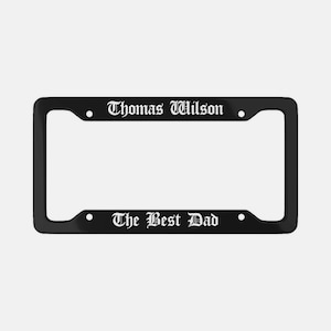 May include: Black metal license plate frame with white text that reads "Thomas Wilson The Best Dad".